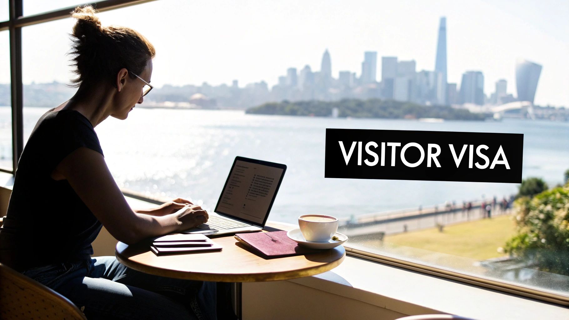 A person works on a laptop at a window overlooking a city skyline and water, with a 'VISITOR VISA' sign.
