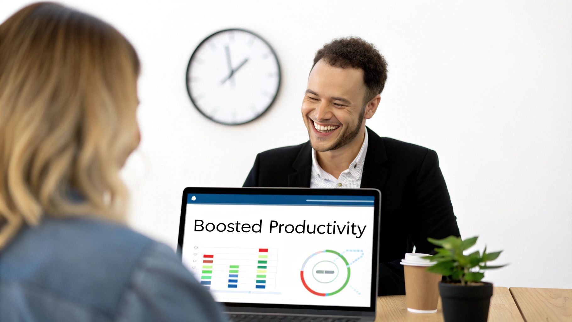 Two smiling colleagues discussing boosted productivity on a laptop with charts and graphs.