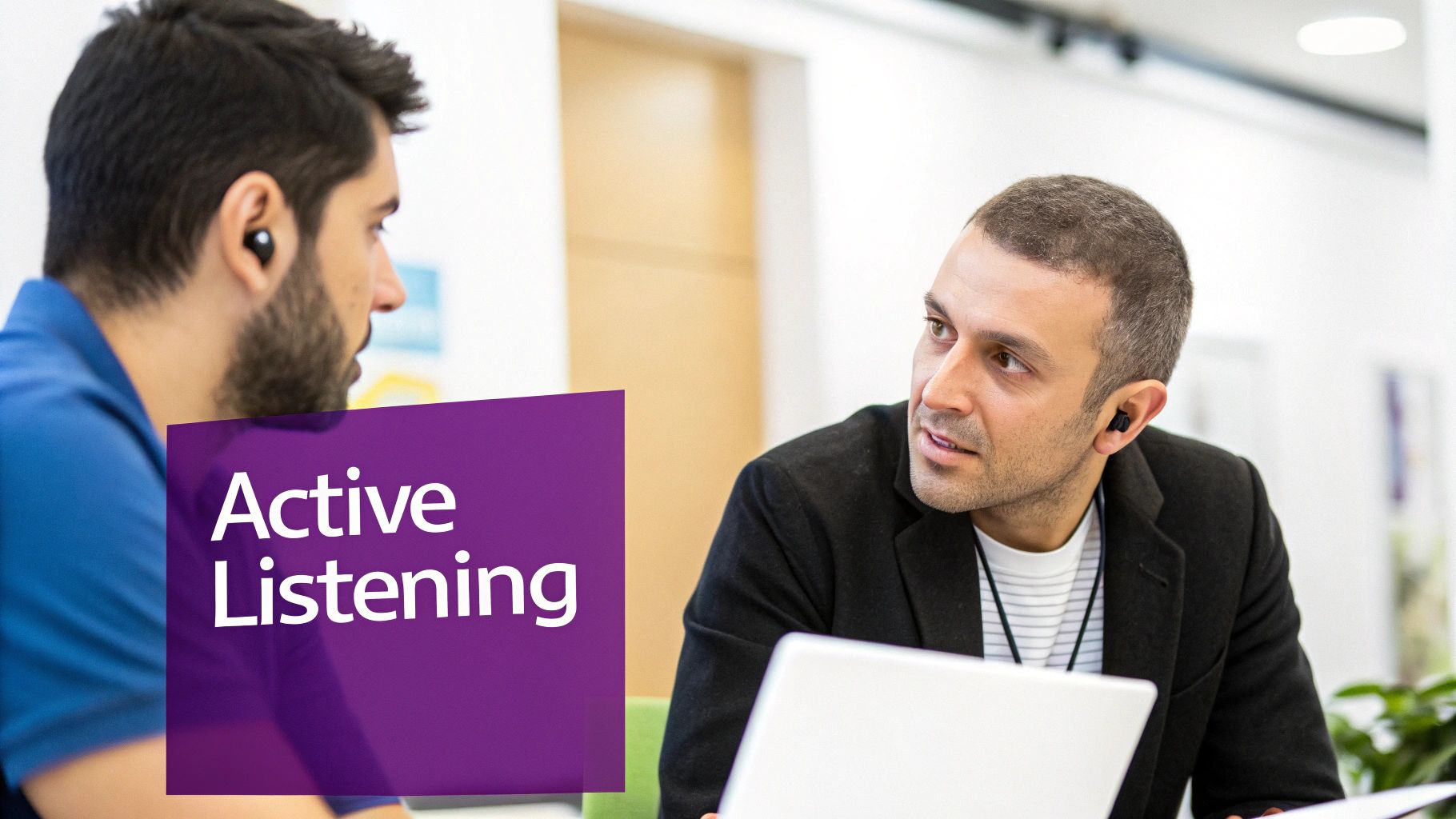 Two men with earbuds engaging in a discussion, highlighting active listening in a professional setting.