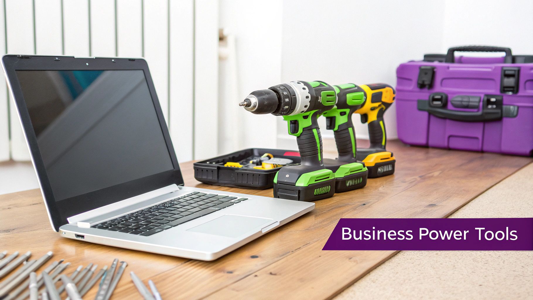 Laptop with cordless power drills and batteries on wooden desk representing business power tools