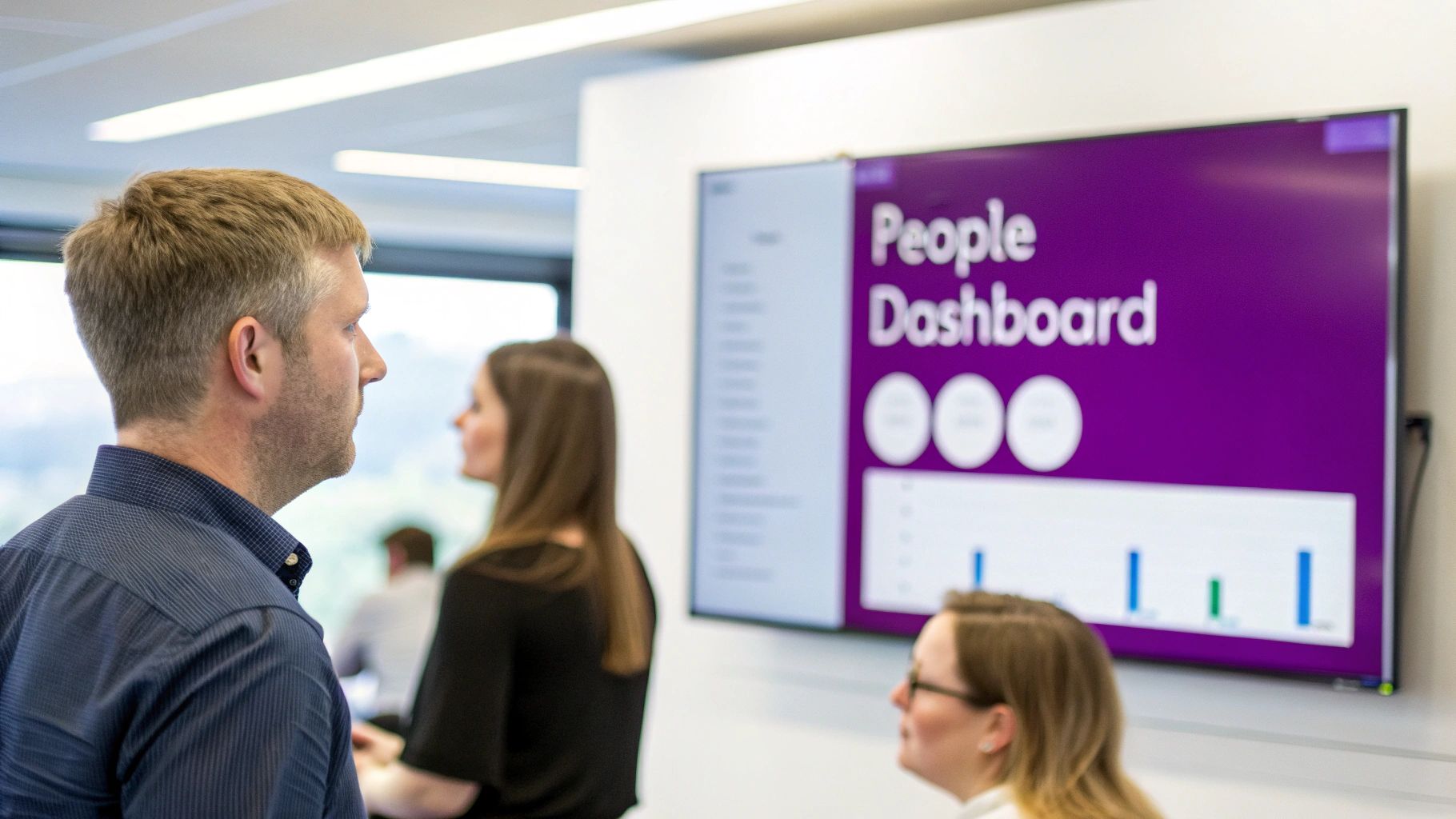 Professionals in a modern office observing a large screen displaying a 'People Dashboard' with data.