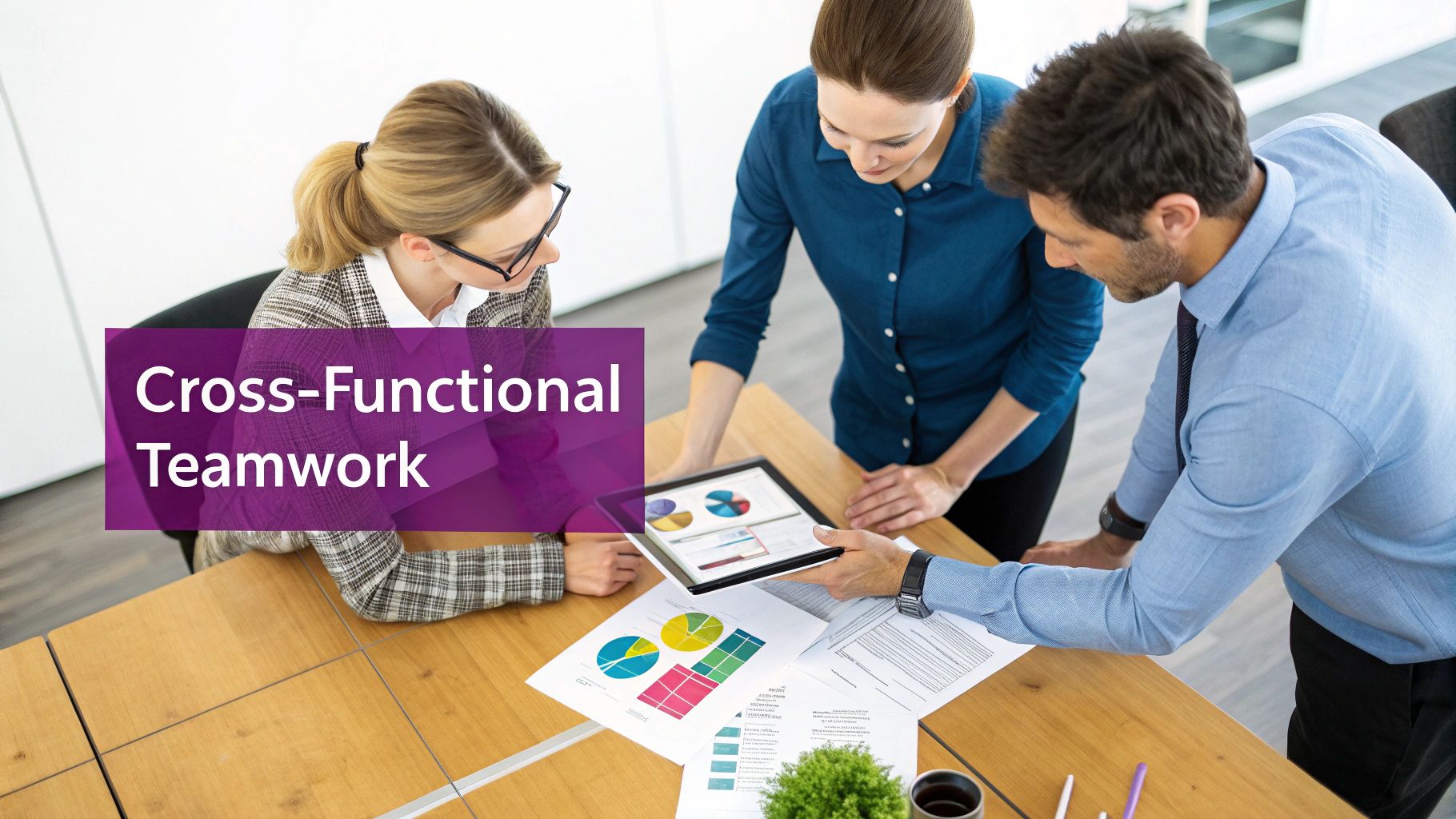 Three professionals collaborating around a table, analyzing charts and data on a tablet and papers.