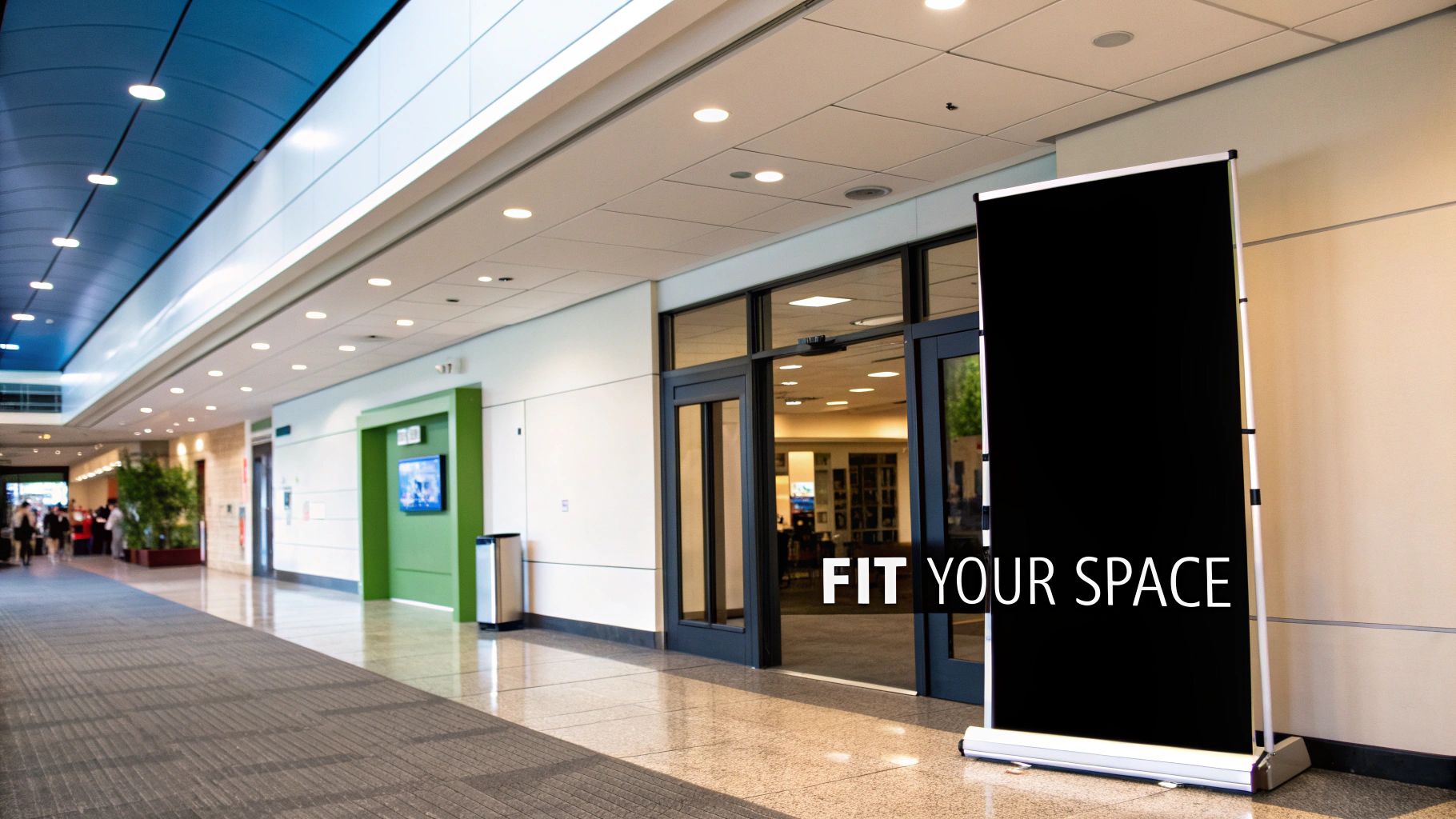 A black pull-up banner with 'FIT YOUR SPACE' text in a bright, modern hallway.