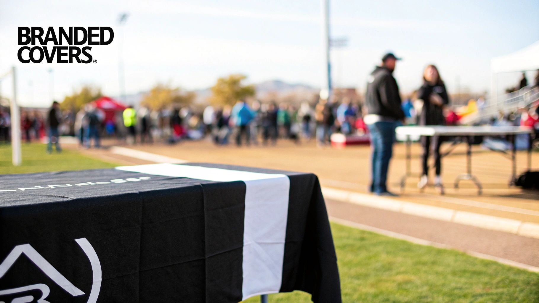 Branded Covers logo on a black table cover with a white stripe at an outdoor event.