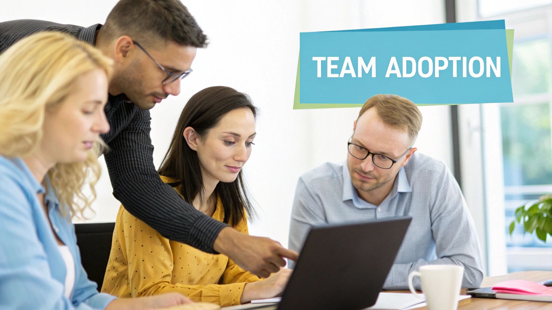 Four diverse colleagues in an office collaborate around a laptop, discussing team adoption strategies.