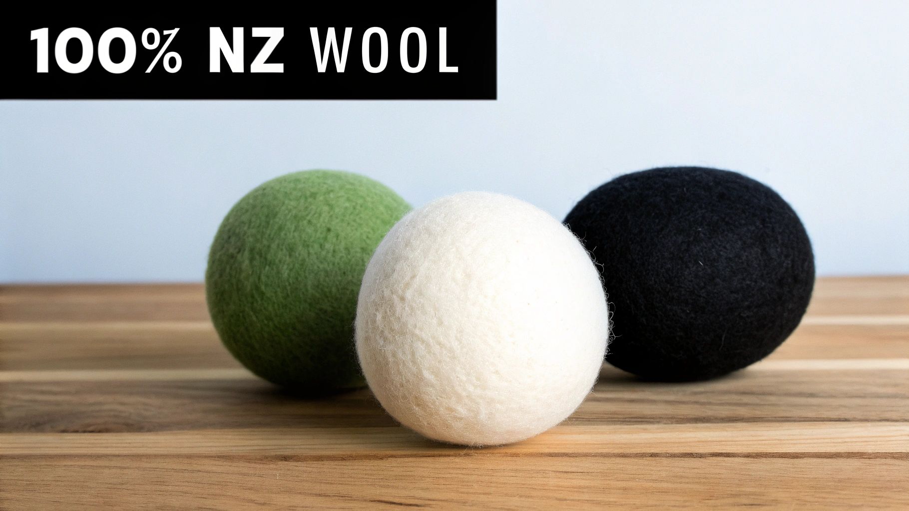 Three natural wool dryer balls (green, white, black) on wood, labeled 100% NZ wool.