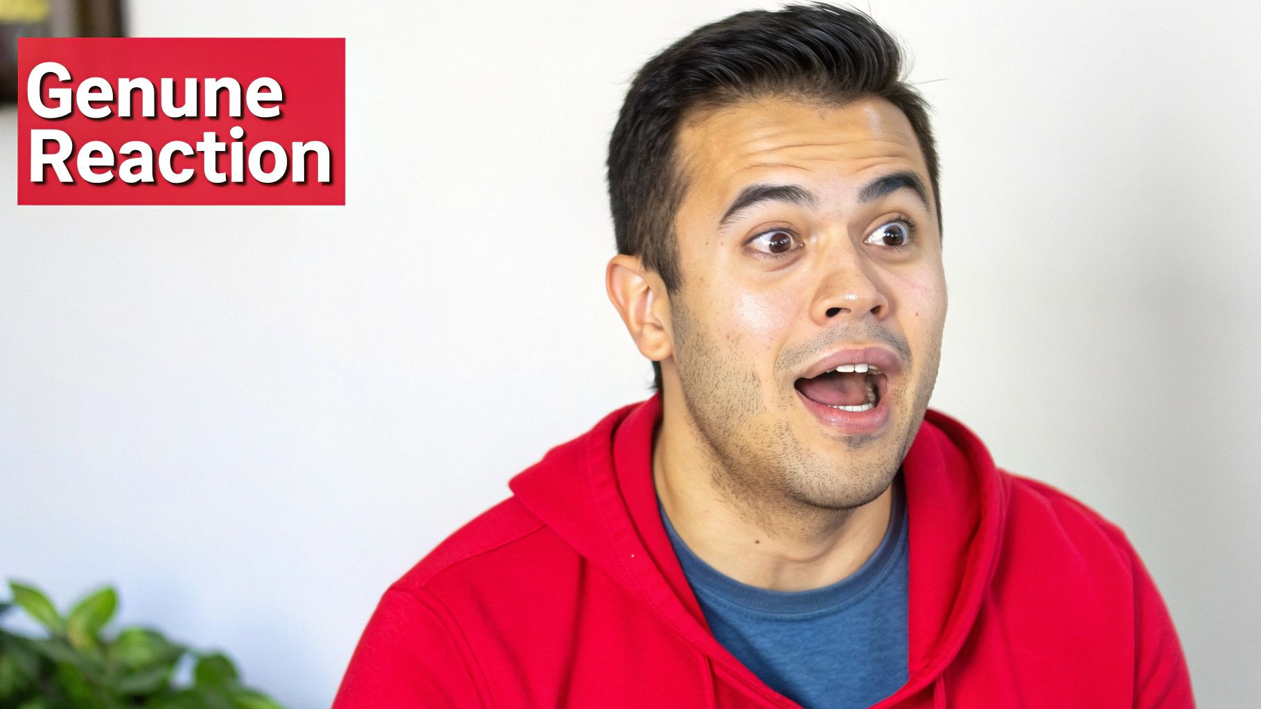 Close-up of a surprised man with wide eyes and open mouth, wearing a red hoodie, with text 'Genuine Reaction'.