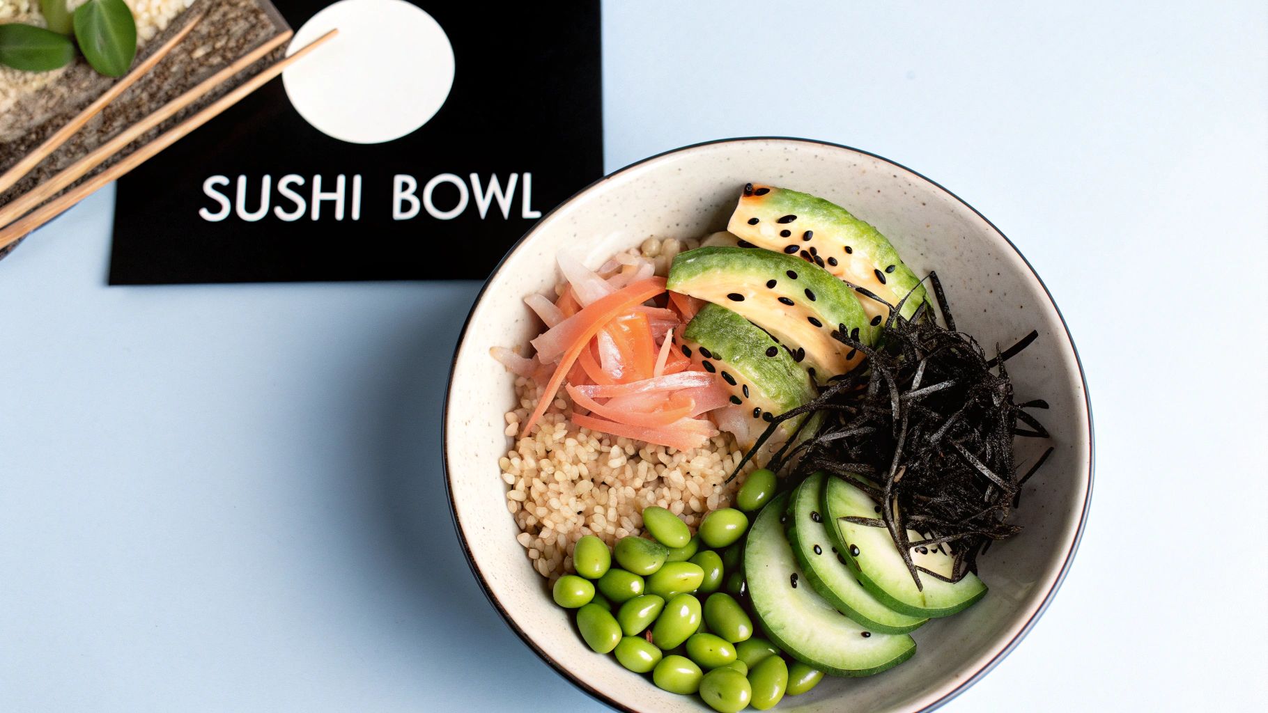 Healthy sushi bowl with brown rice, sliced avocado, edamame, pickled ginger, and seaweed.