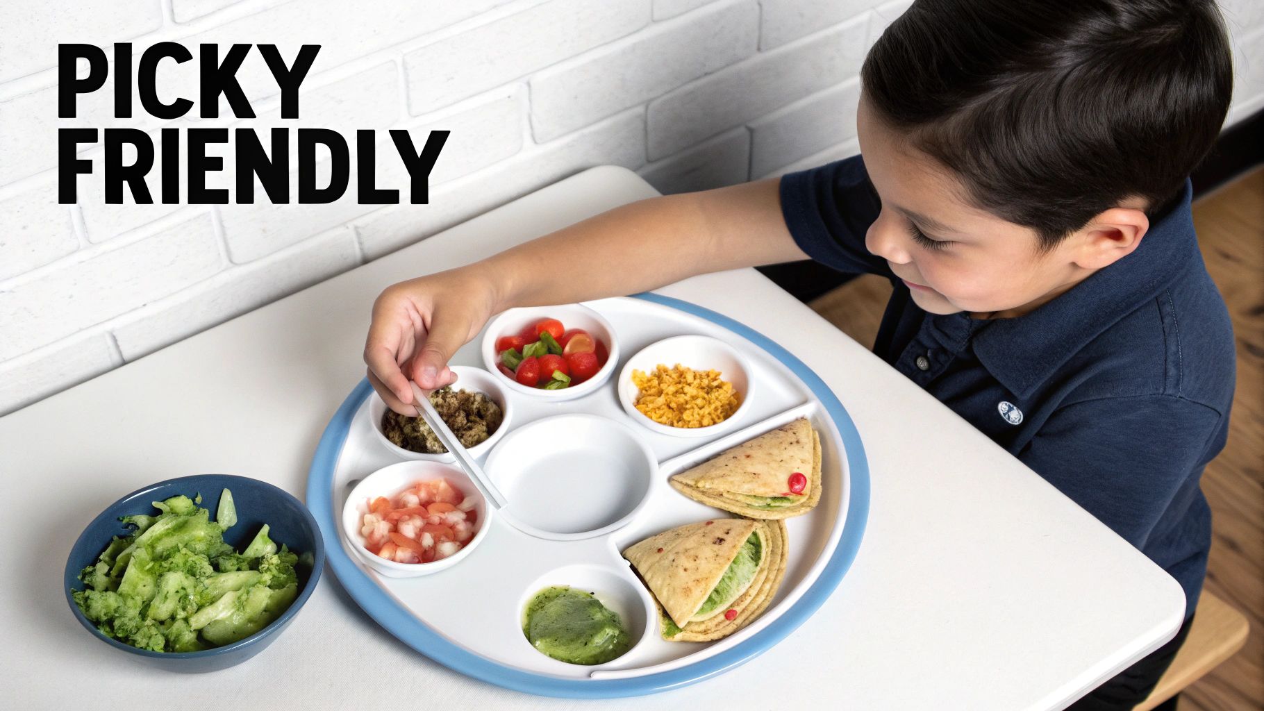 Young boy at a table eating from a divided plate filled with a variety of healthy foods.