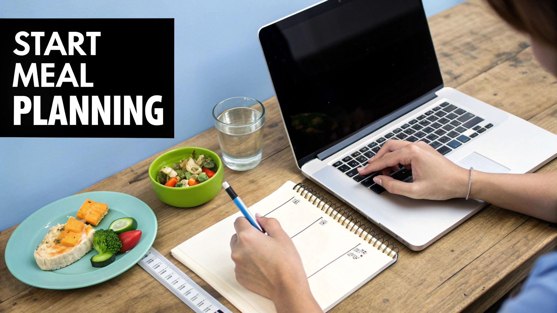 Person creating a meal plan at a desk with a laptop, healthy food, and a notebook.