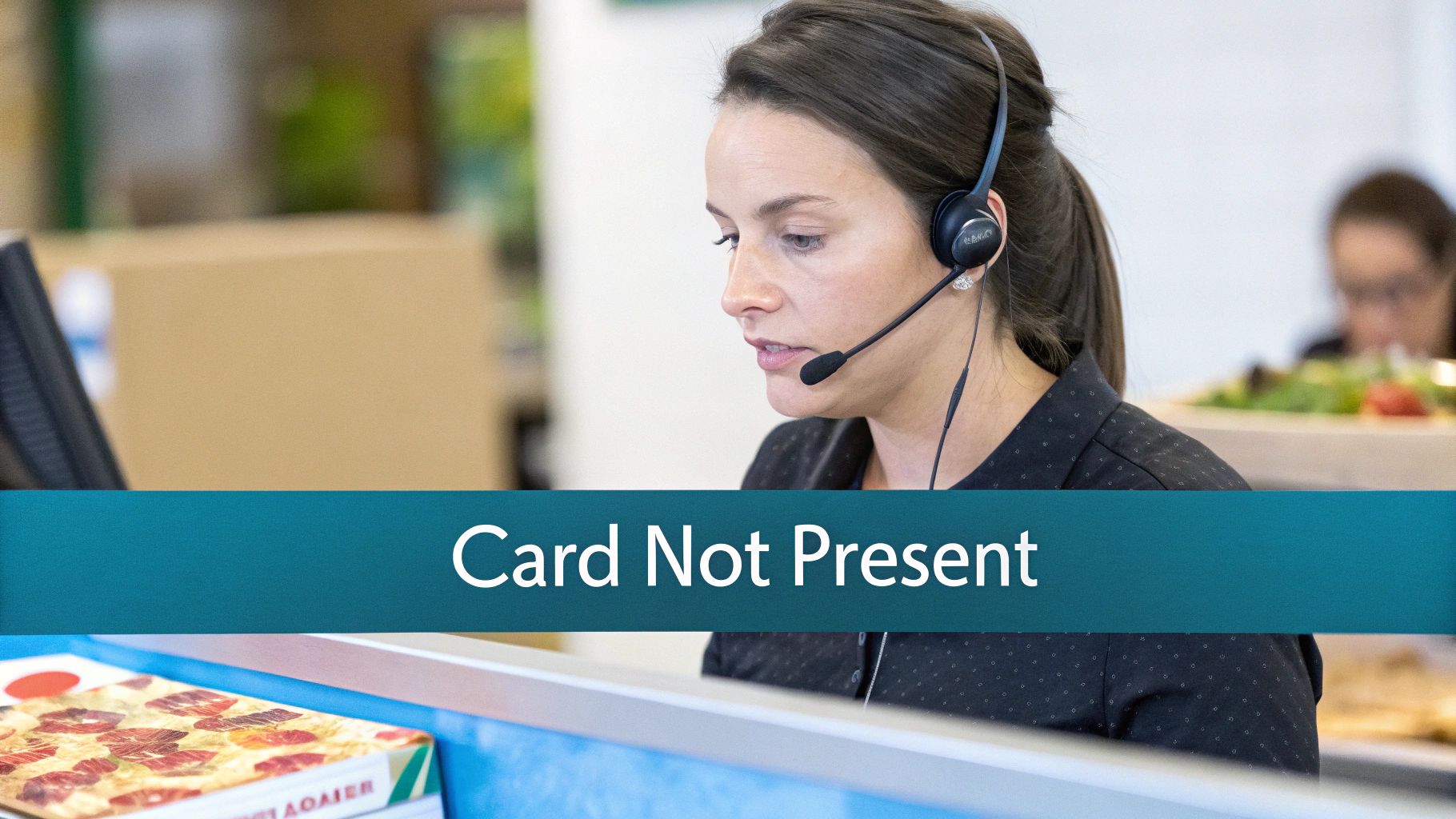 A focused woman wearing a headset and microphone works at a desk in a customer service office.