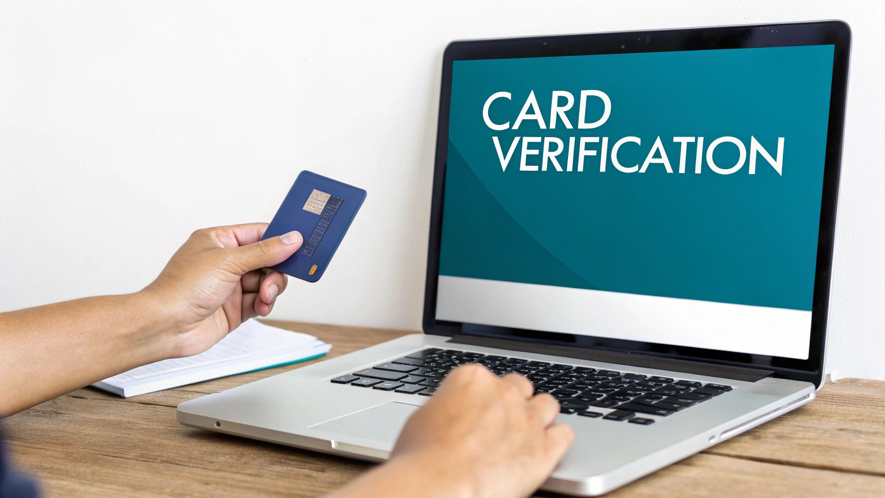 A person holds a blue payment card while typing on a laptop with 'CARD VERIFICATION' on screen.