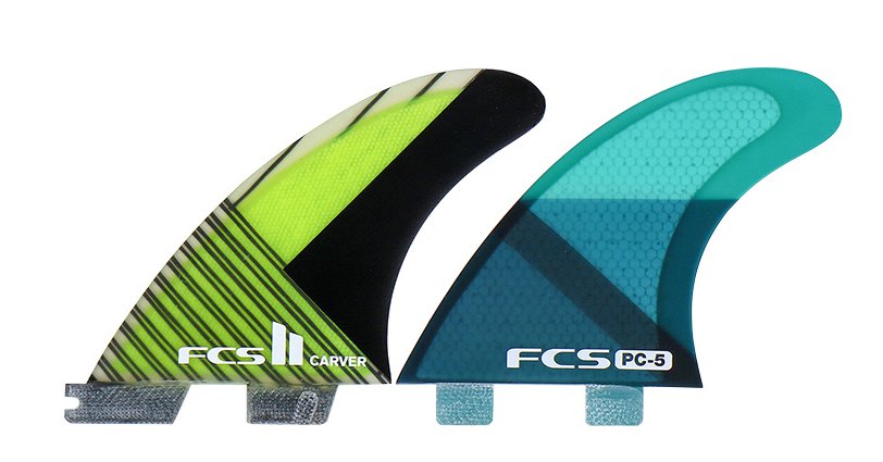 Two FCS surf fins are displayed: a green and black FCS II Carver, and a teal FCS PC-5.