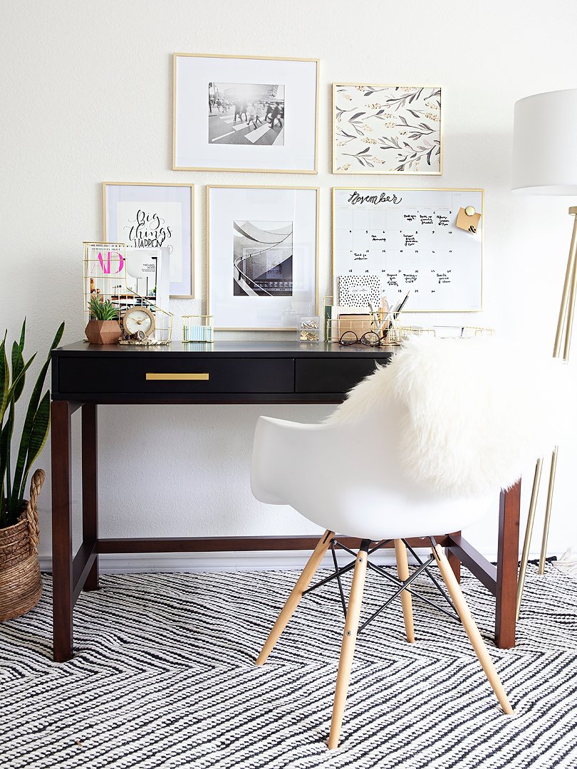 A stylish and organized home office setup featuring a dark desk, white chair, and wall art.