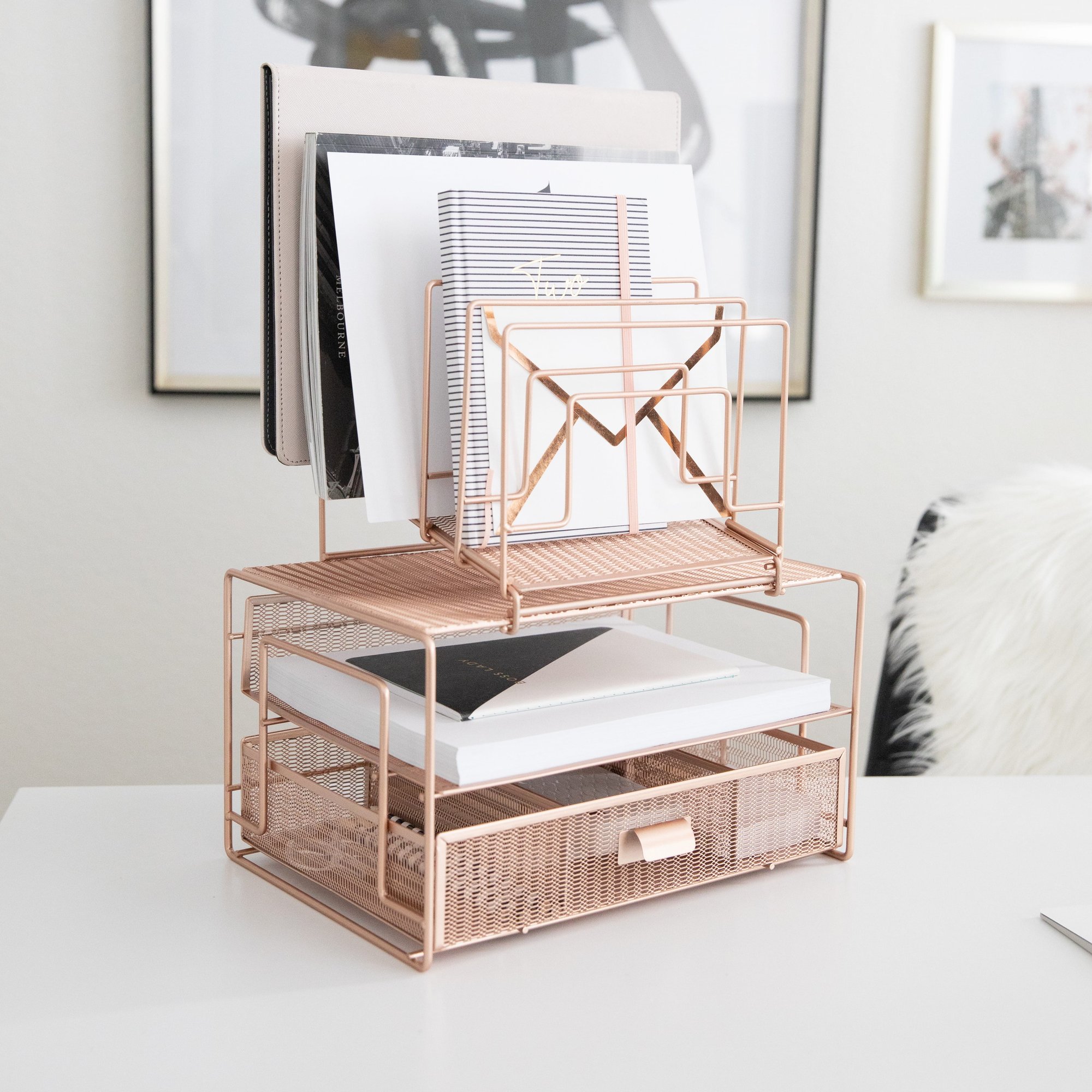 Elegant rose gold mesh desk organizer filled with notebooks and papers on a clean white table.