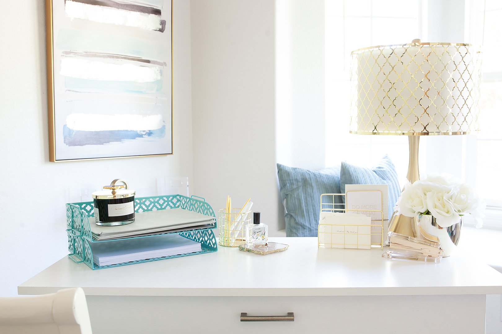 A bright and organized home office desk featuring various teal and gold decorative accessories.