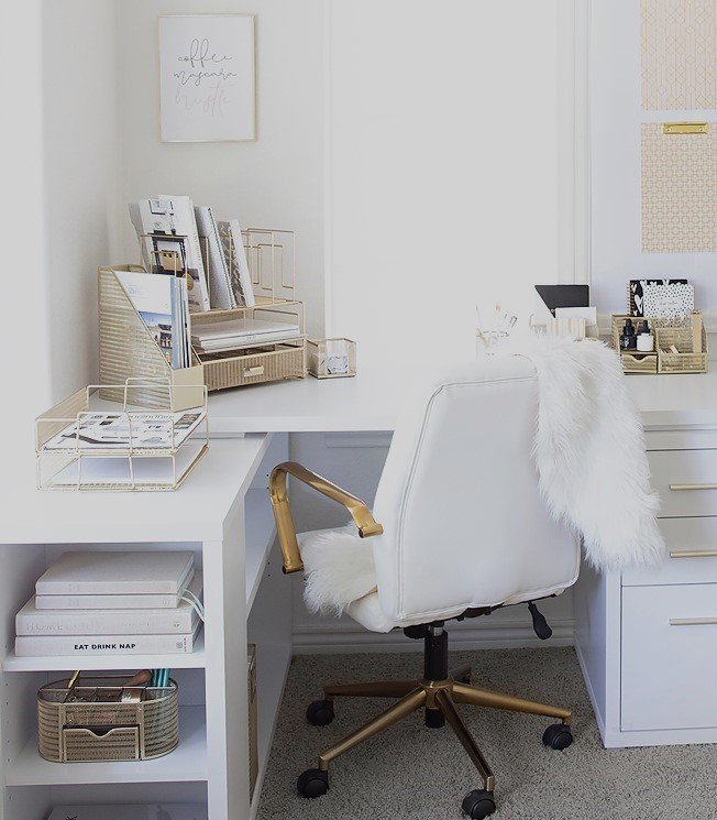 A bright home office featuring a white L-shaped desk, a gold-accented chair, and organized desk accessories.