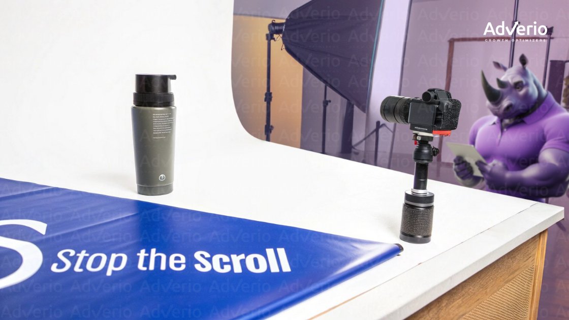 A product photography studio setup with a green bottle, camera, and a blue 'Stop the Scroll' banner.