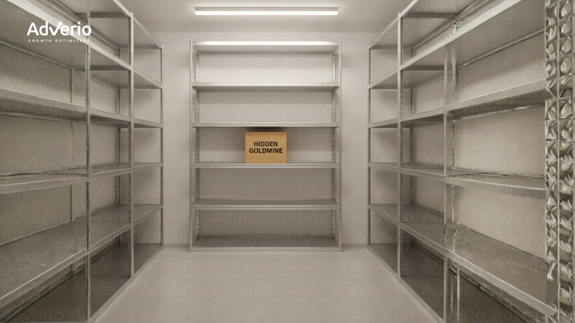 An empty storage room with metal shelving units, featuring a single cardboard box labeled "HIDDEN GOLDMINE".