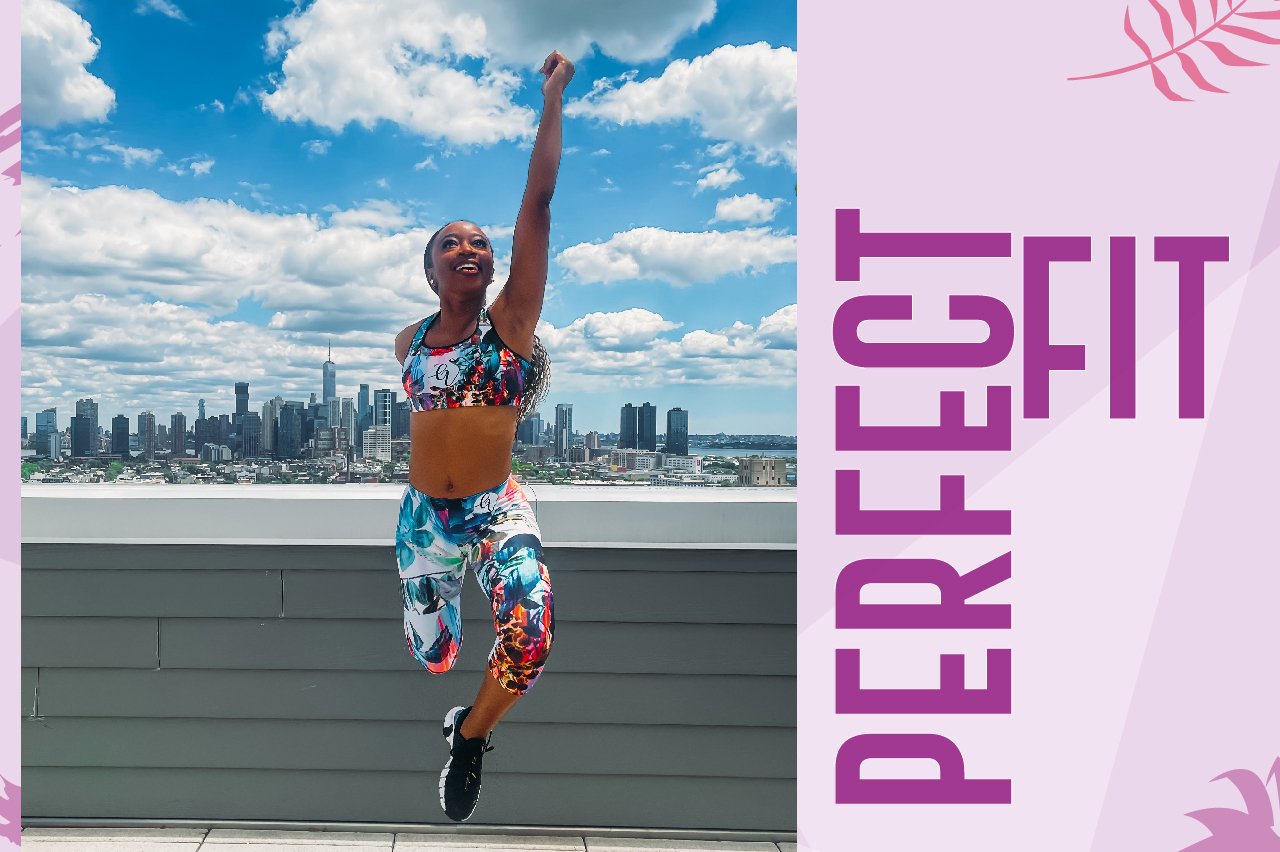 A woman with a prosthetic leg jumps joyfully in colorful activewear on a rooftop with a city skyline.