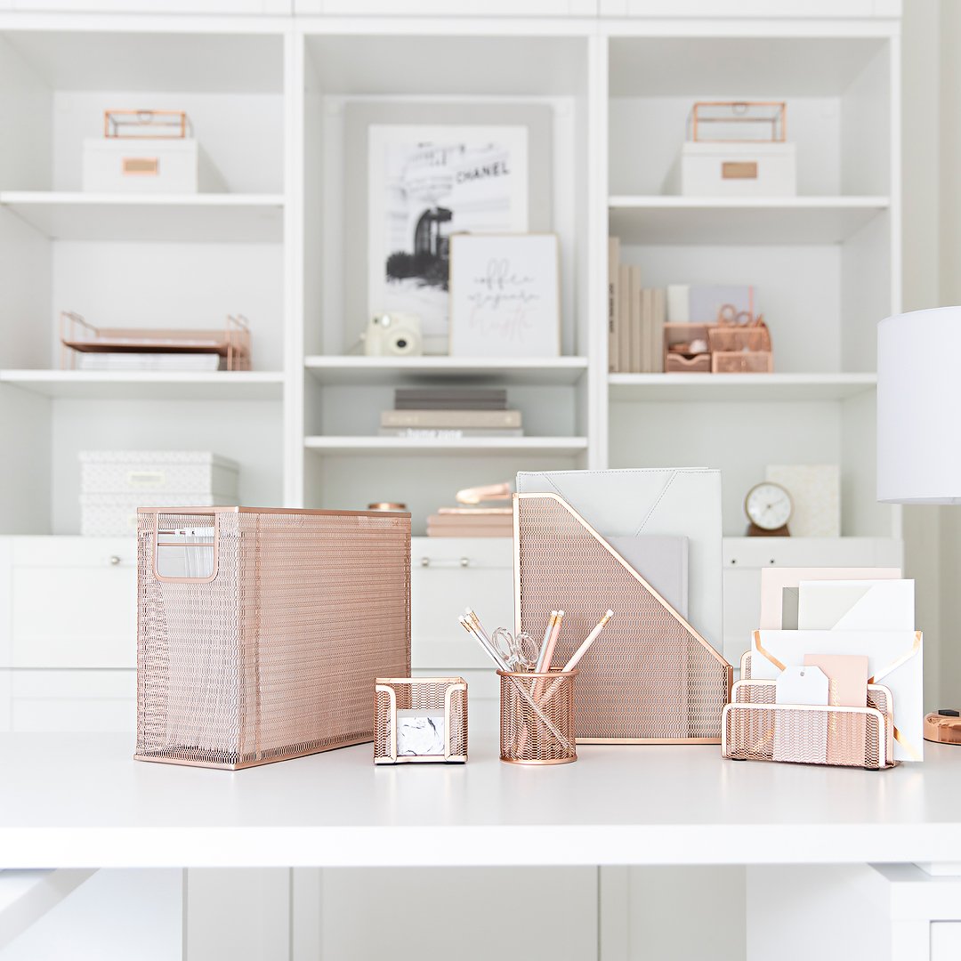 Organized white office desk with rose gold mesh organizers and matching stationery.