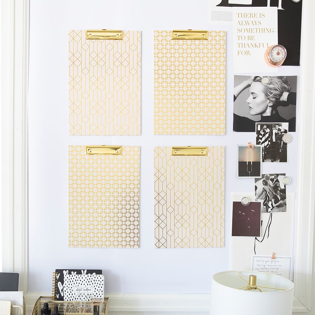 Four gold geometric patterned clipboards, photos, and notes create a decorative bulletin board.