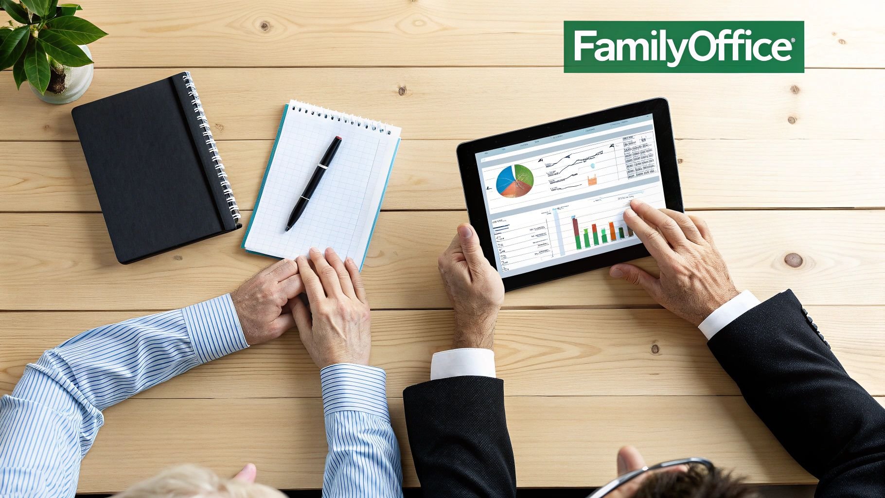 Overhead view of two people discussing financial data on a tablet during a business meeting.