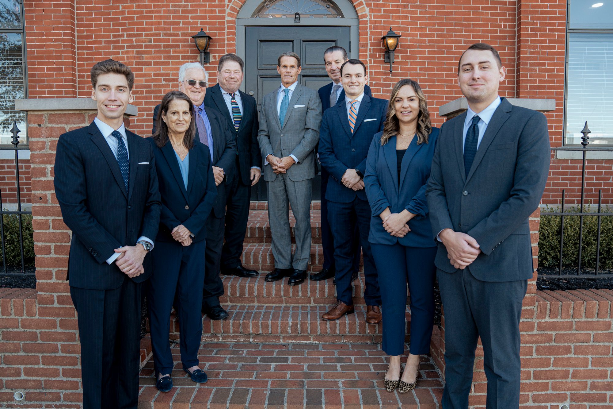 Our entire team in business attire smiling on brick steps in front of a building.