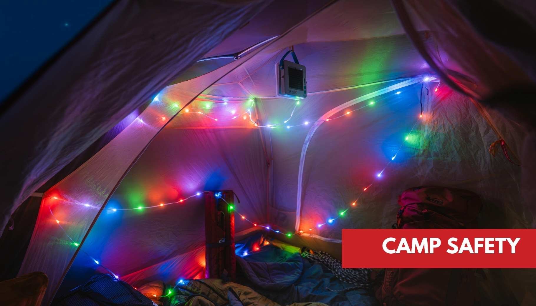 A vibrant camping tent interior at night, decorated with multi-colored fairy lights and camping gear.