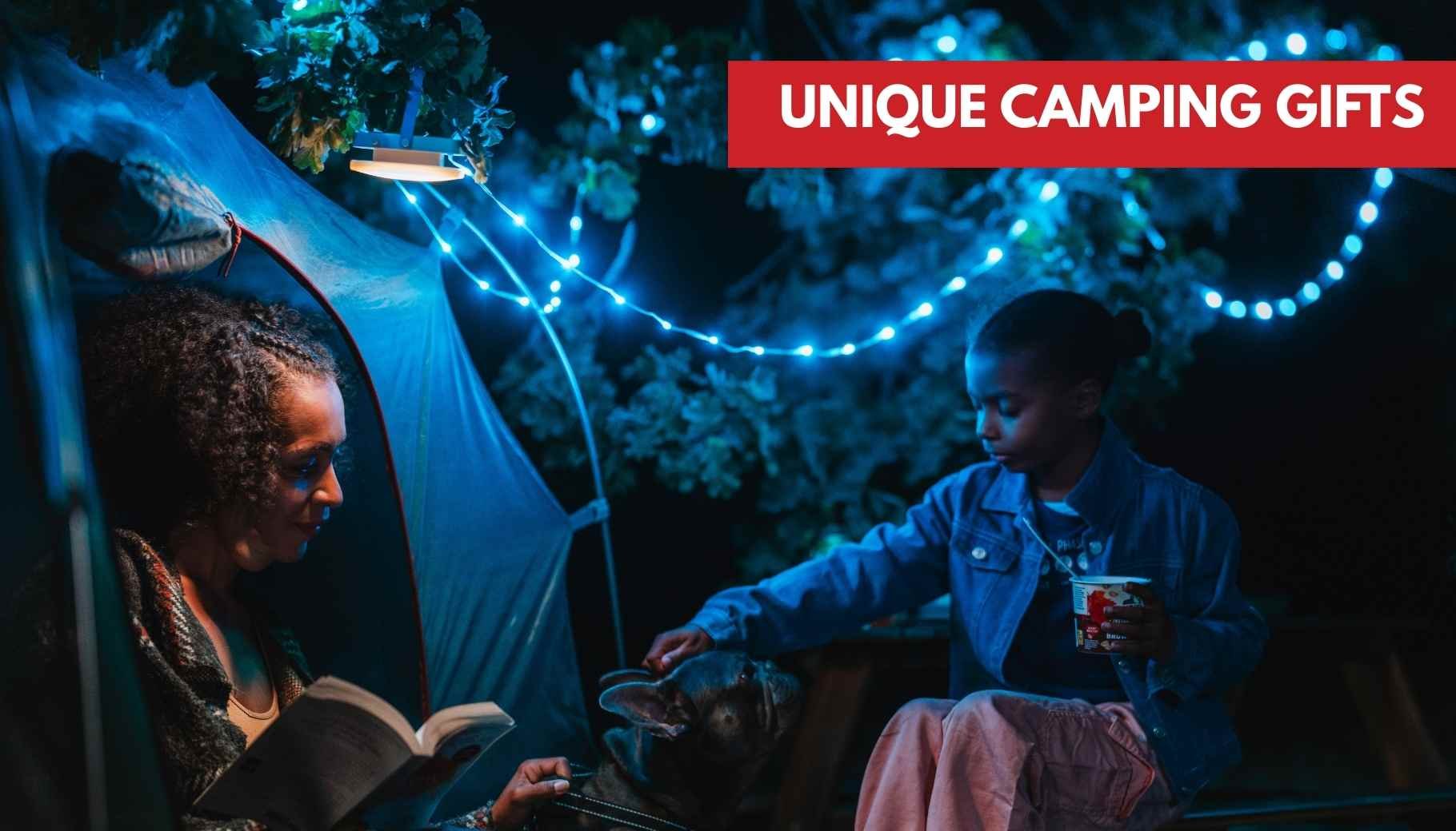 Woman reads in a tent while a child pets a dog, illuminated by blue fairy lights at night.