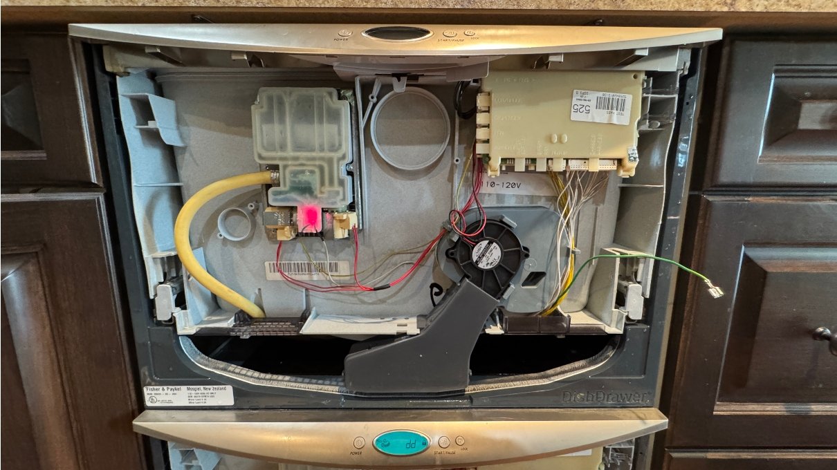 Internal view of a Fisher & Paykel DishDrawer dishwasher with components and wiring exposed, showing a red light.