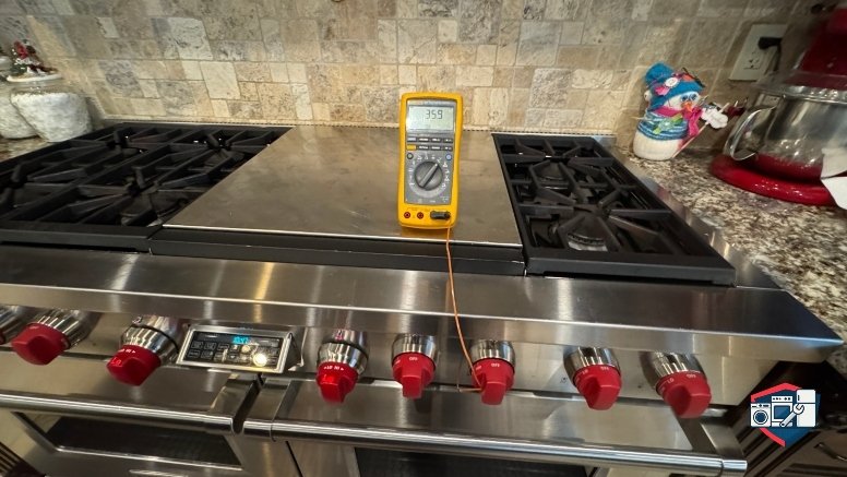 A yellow digital thermometer showing 359 on a stainless steel professional kitchen range with red knobs.