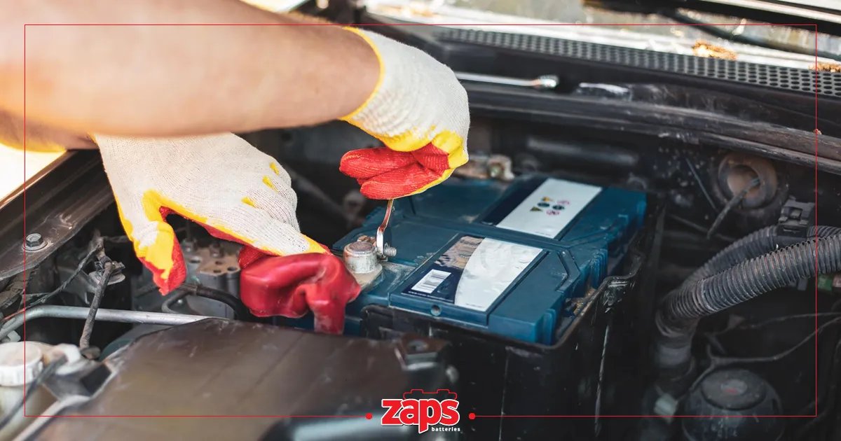 Χέρια με προστατευτικά γάντια εργάζονται στην μπαταρία ενός αυτοκινήτου, κάνοντας συντήρηση ή επισκευή στον κινητήρα.