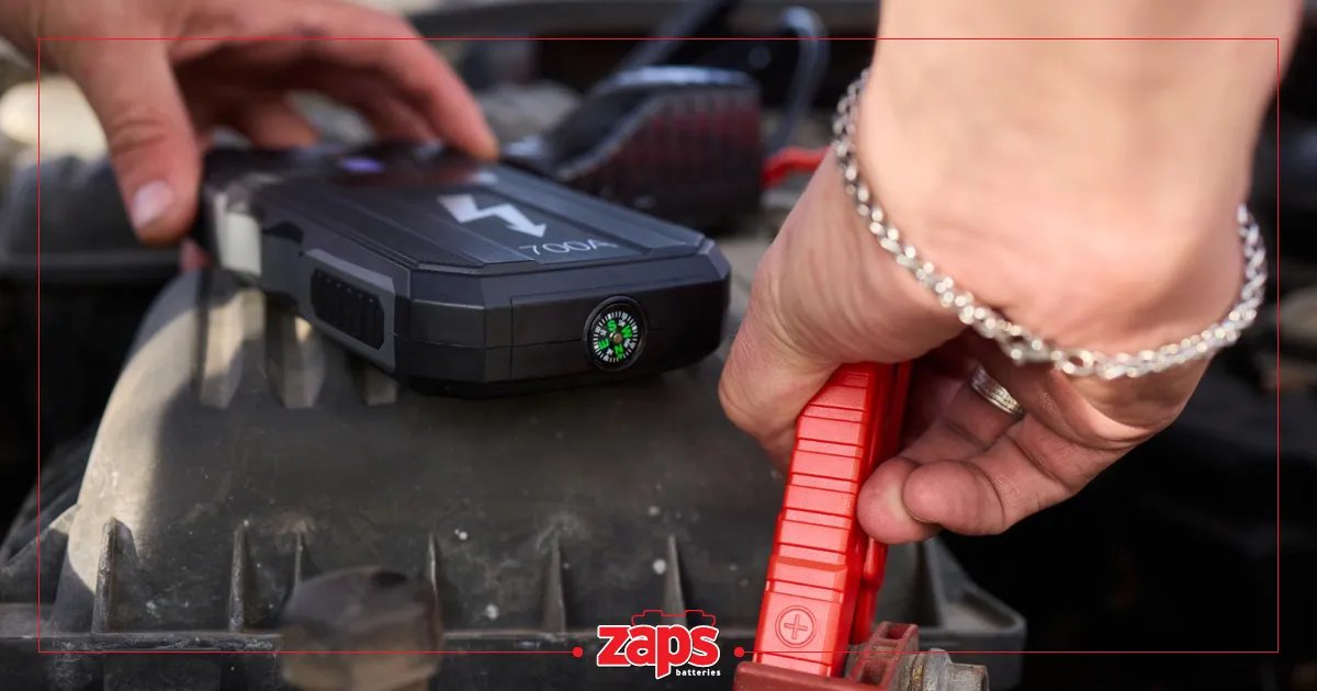Άτομο συνδέει φορητό εκκινητή αυτοκινήτου με κόκκινο κλιπ σε ακροδέκτη μπαταρίας, για εκκίνηση οχήματος.
