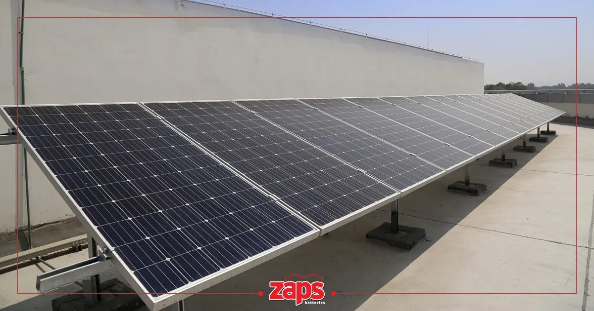 Μια μεγάλη σειρά από μαύρα ηλιακά πάνελ εγκατεστημένα σε μια επίπεδη οροφή με λευκό τοίχο κτιρίου.