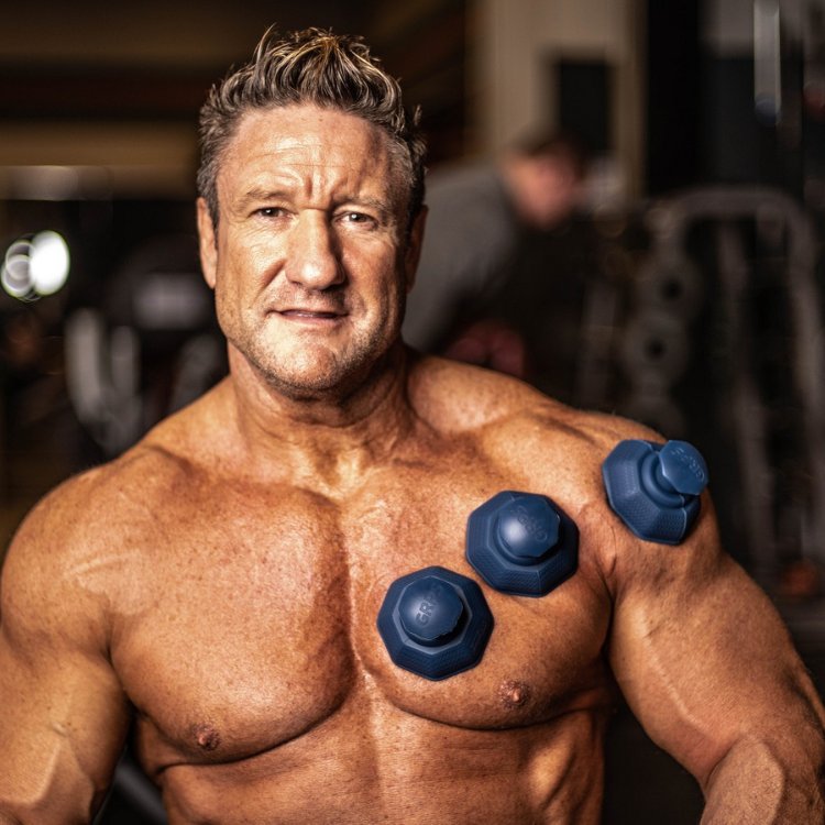 Muscular man in a gym with three blue cupping therapy devices on his chest and shoulder.