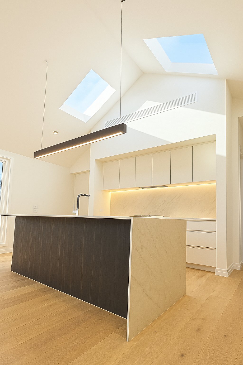 Modern kitchen with a large island, under-cabinet lighting, and vaulted ceiling with skylights.