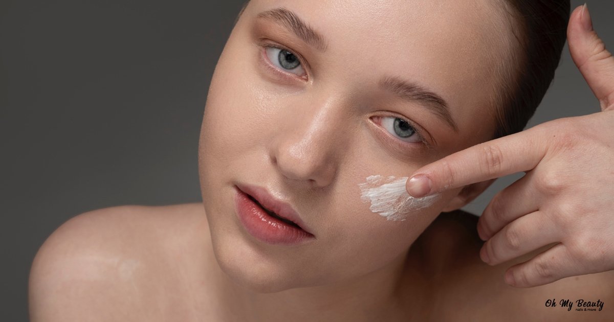 Καλύτερο primer προσώπου: Ο Απόλυτος Οδηγός για Τέλεια Βάση Γυναίκα εφαρμόζει λευκό primer προσώπου στο μάγουλό της με το δάχτυλο