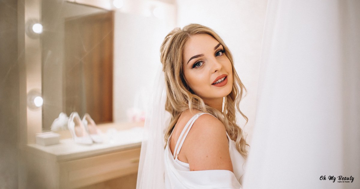 Ρομαντικό Νυφικό Μακιγιάζ: Ο Απόλυτος Οδηγός για το 2026 Όμορφη νύφη με ξανθά μαλλιά και πέπλο, χαμογελάει καθώς ετοιμάζεται για τον γάμο της, με μακιγιάζ.