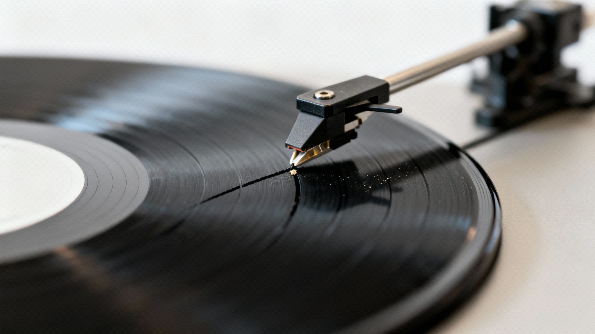A turntable's needle plays a vintage black vinyl record with visible grooves and some dust.