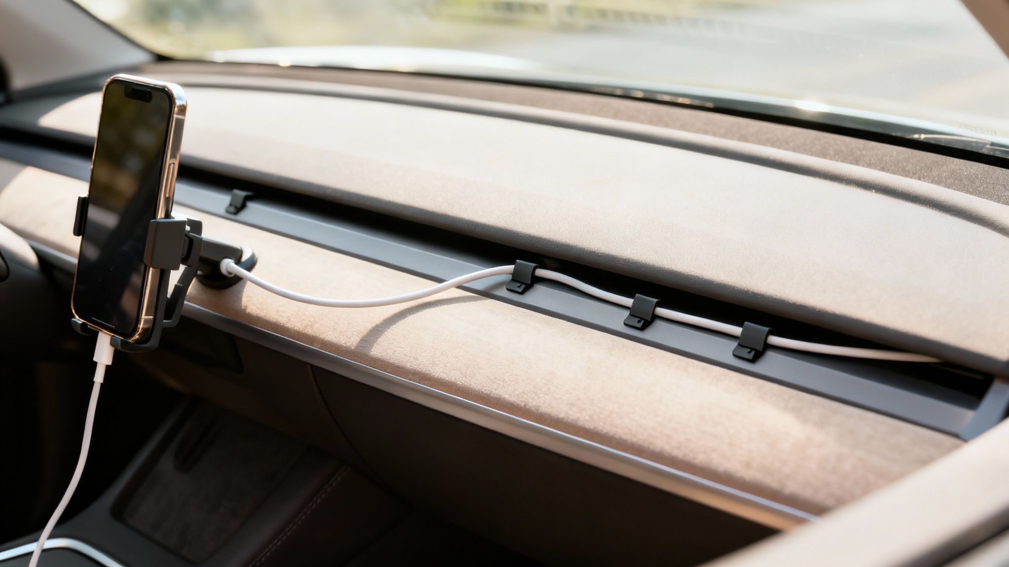 Smartphone mounted in a car dashboard, with charging cable neatly organized by clips.