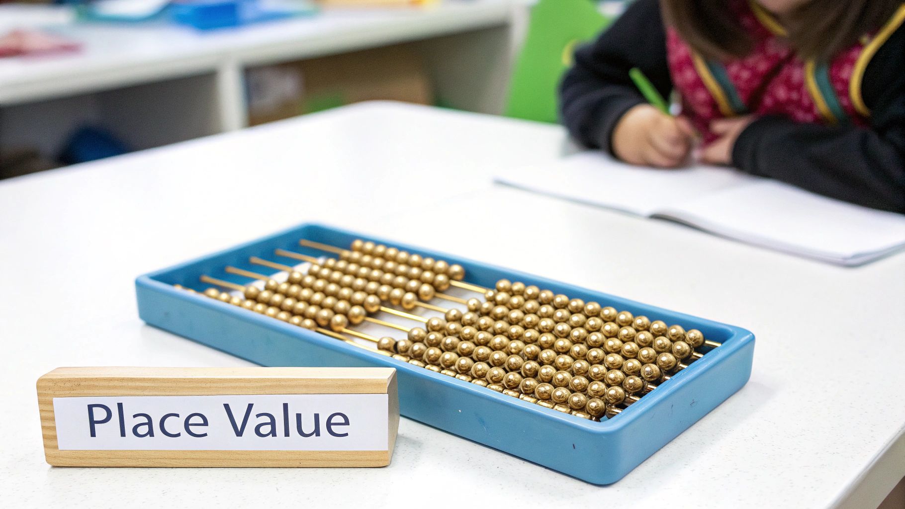 Golden bead Montessori math manipulatives in blue tray with place value label for preschool learning