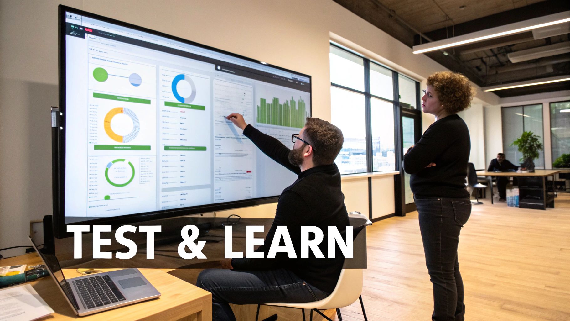 Two marketing professionals analyze data on a large screen in a modern office, emphasizing testing and learning.