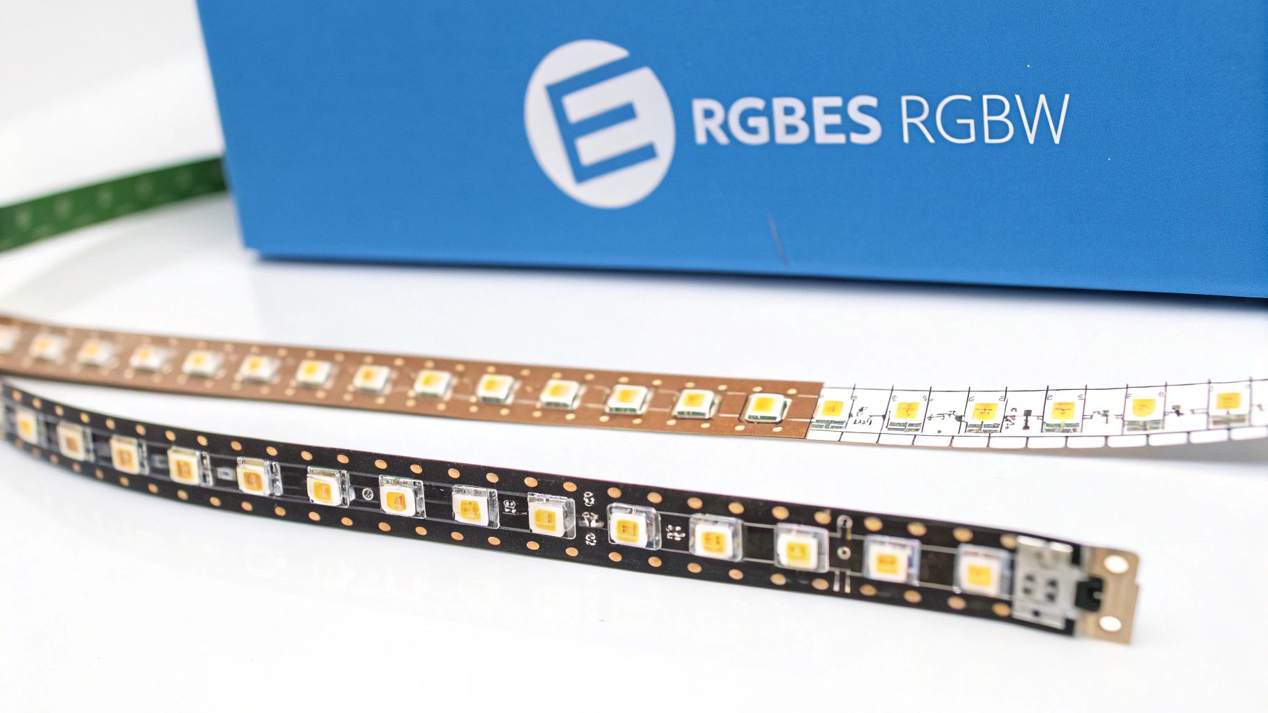 Két RGB LED szalag, egy barna és egy fekete, egy kék, RGB feliratú doboz előtt.