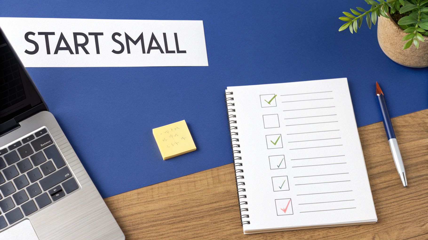 Desk with 'START SMALL' sign, laptop, and a checklist notebook with green checkmarks and one red.