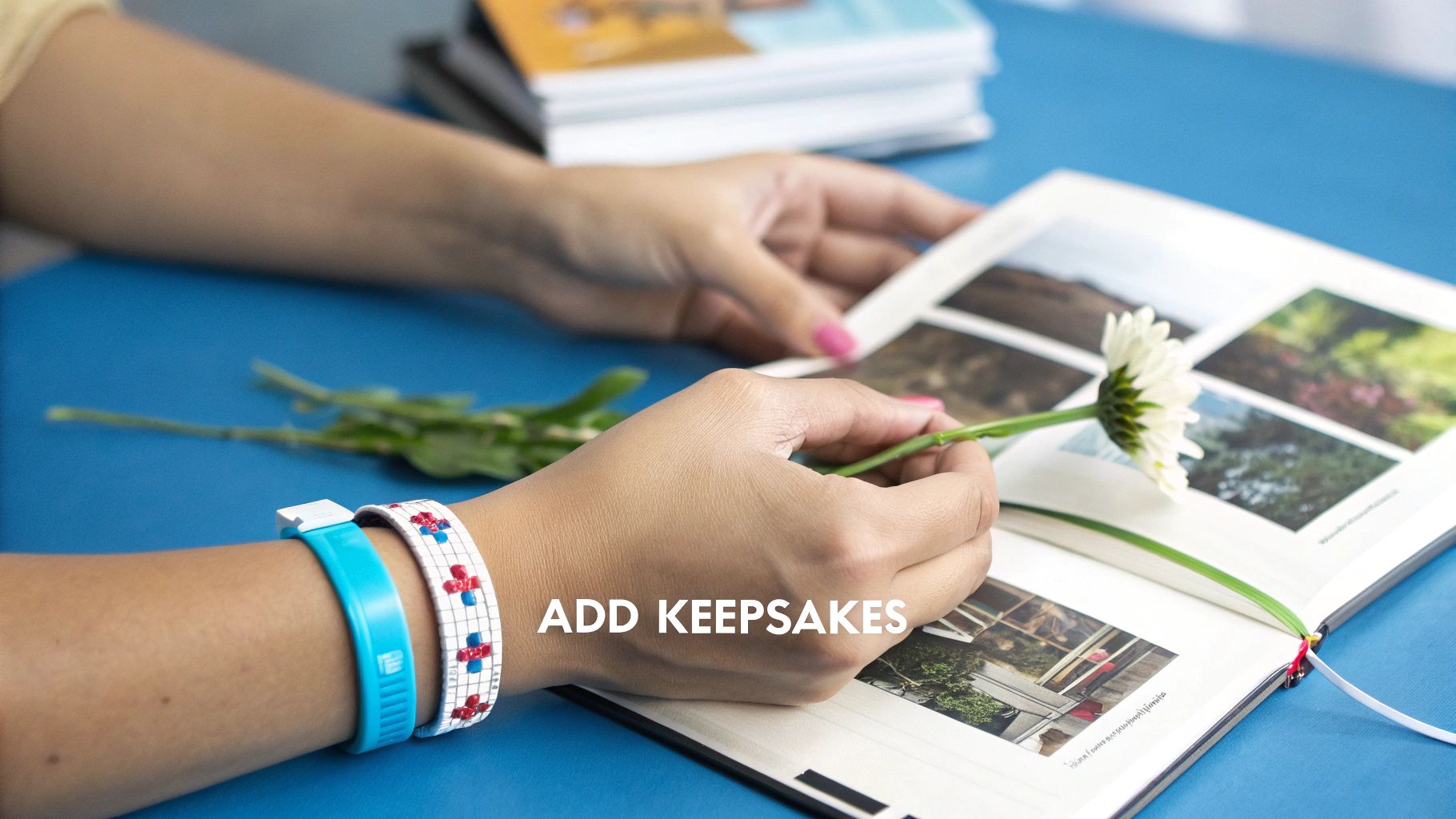 A baby's hand holding onto their parent's finger next to a baby memory book.