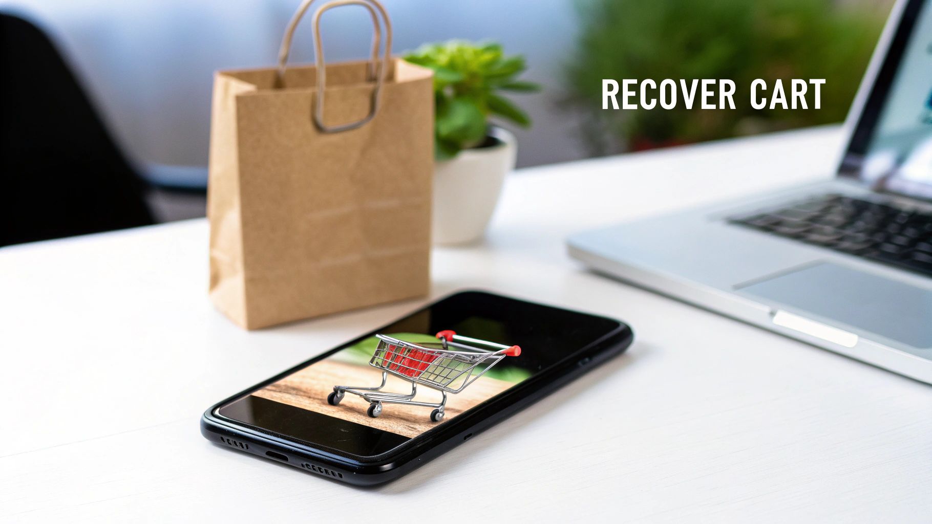 A smartphone displaying a shopping cart on its screen, with a paper bag and laptop in the background, representing cart recovery.