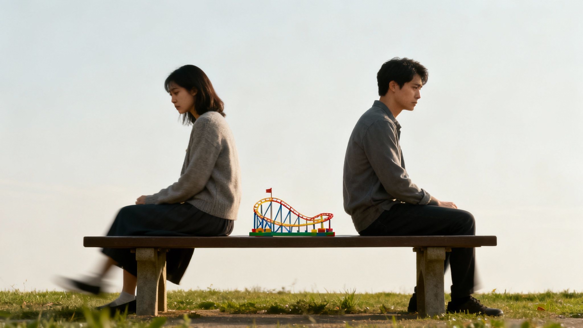 A man and a woman sit back-to-back on a bench, a toy roller coaster between them, depicting a strained relationship.