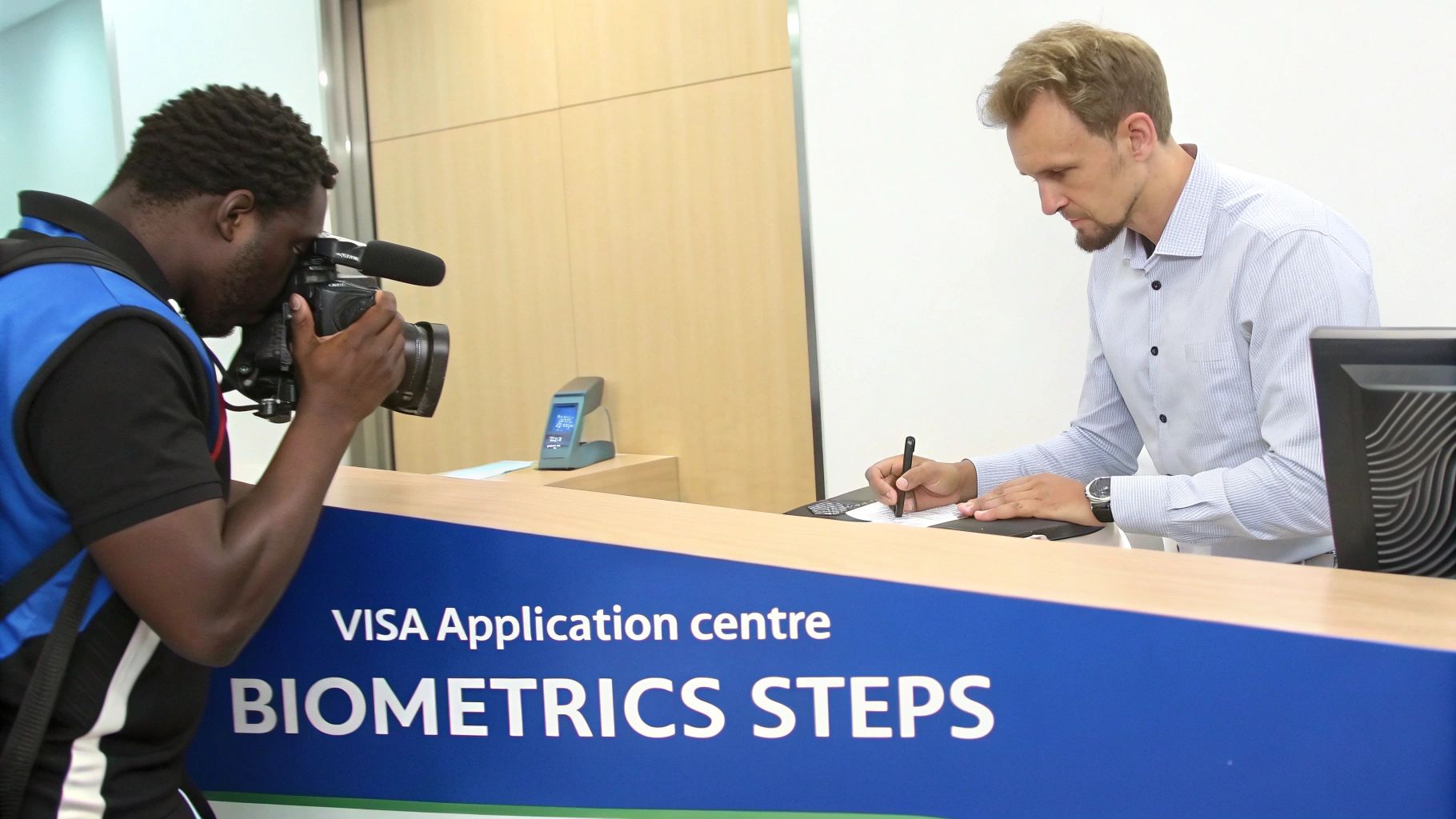 A journalist records a man signing documents at a visa application center for biometrics.
