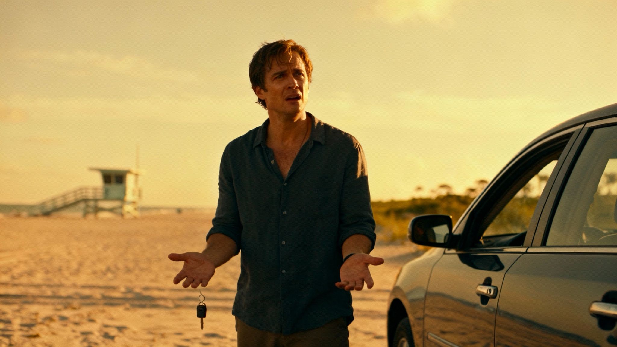 A confused man on a sandy beach holding car keys, with a car and lifeguard stand at sunset.